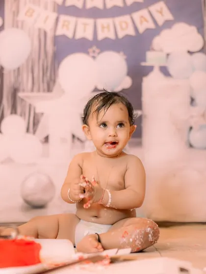A classic boy's first birthday setup with a blue and white theme. The backdrop features clouds and a "Happy Birthday" banner, ideal for a simple and sweet cake smash session.