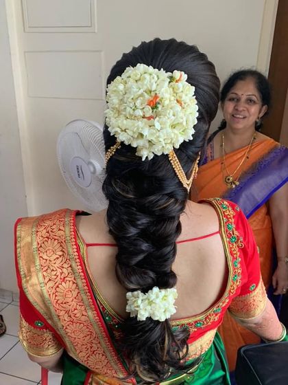 A classic South Indian bridal hairstyle with a neat braid, jasmine gajra, and traditional gold hair jewelry, perfect for a muhurtham ceremony.