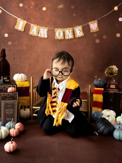 Wingardium Leviosa! This magical Harry Potter themed first birthday shoot is perfect for little wizards. The setup includes a Gryffindor scarf, glasses, a wand, and a backdrop that feels like Hogwarts.