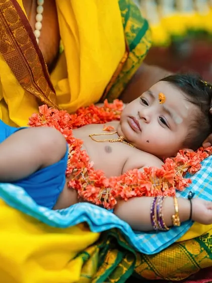 This shot captures the baby being adorned with a flower garland, a beautiful part of many traditional Indian ceremonies.