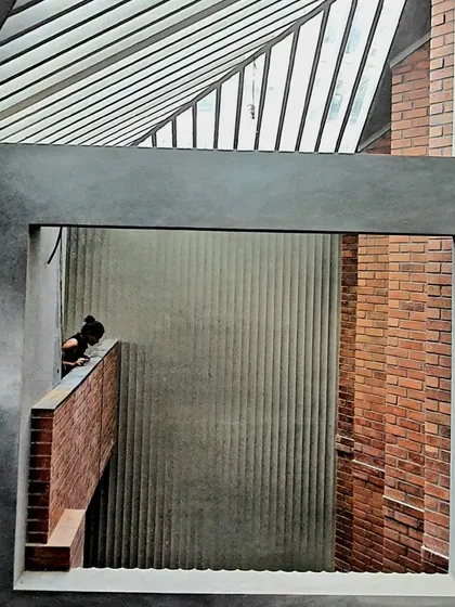 A framed view within the Brick House, where layers of brick, concrete, and a slatted skylight create a complex interplay of textures and light.
