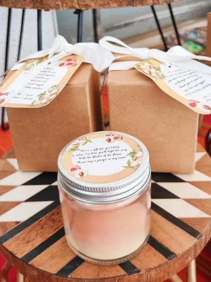 A close-up of the custom candle we made for a client's baby shower. The personalized message on the lid and tag adds a heartfelt touch.