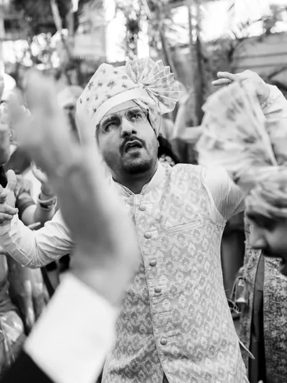 A black and white shot from the baraat that focuses on the groom's friend dancing with full energy. Monochrome can really amplify the emotion and action in a chaotic scene.