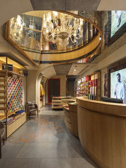 A mirrored ceiling at Ahujasons reflects the grand chandelier and the store's upper level, creating an illusion of greater height and volume. This design choice adds a layer of opulence and visual complexity to the retail experience.