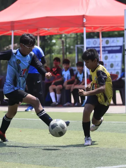 A thrilling semi-final match for our U-15 team. A player skillfully shields the ball from a defender, showcasing the strength and control needed in high-pressure games.