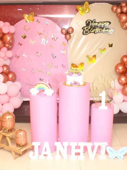 A pretty-in-pink butterfly-themed first birthday. This setup uses two arched backdrops, rose gold and pink balloons, and butterfly decals to create a soft and feminine look.