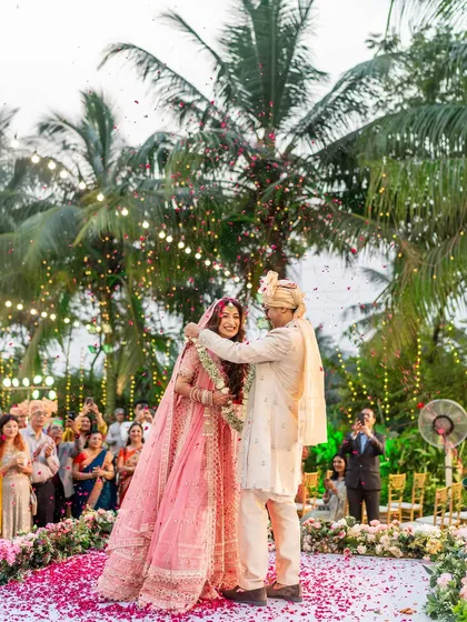 The successful garland exchange, with both bride and groom smiling, surrounded by a shower of flowers.