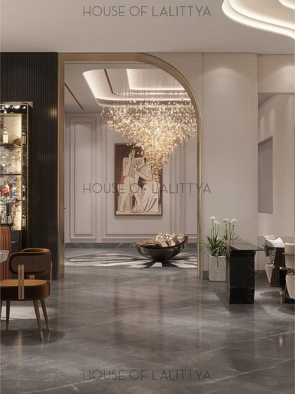 We design spaces that flow effortlessly into one another. Here, a gracefully arched opening frames the view from the bar area into the main living space, where a stunning chandelier hangs as a focal point. The continuous marble flooring unifies the two zones.