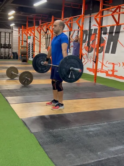 A client holding the hang position before initiating the second pull of the snatch. This isometric hold builds strength and positional awareness.