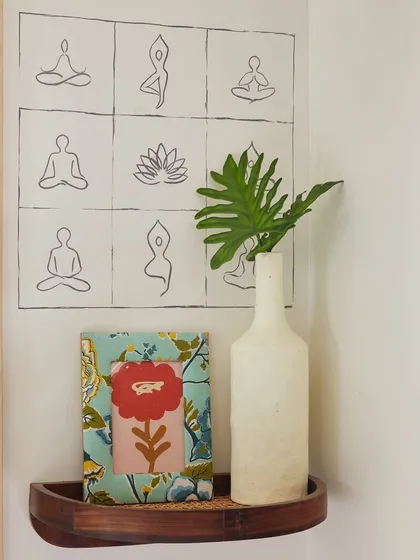 The soul of a space is often found in its smallest details. In this corner, I incorporated hand-painted graffiti of yoga poses to create a moment of calm amidst a busy schedule. This simple artwork, paired with a textured frame and an earthy vase on a wooden shelf, adds a personal, grounding touch that is both beautiful and durable enough for a mobile environment.