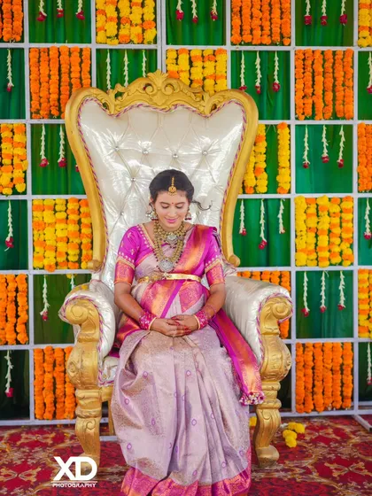A quiet moment of reflection for the mother-to-be, seated elegantly on the ceremonial chair, surrounded by traditional decorations.