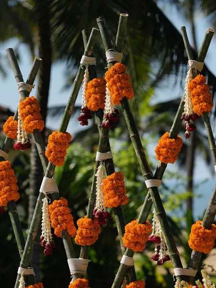 A close-up of the marigold garlands on the bamboo structure, a perfect fusion of traditional flowers and rustic, beachy elements.