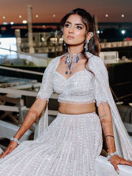 A powerful and confident pose from the bride at her sangeet. The full glam makeup enhances her features and complements the dramatic, all-white outfit.