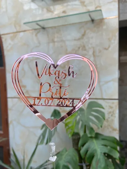A clear, outdoor shot of the "Vikash & Priti" topper, with natural light highlighting the rose gold finish.