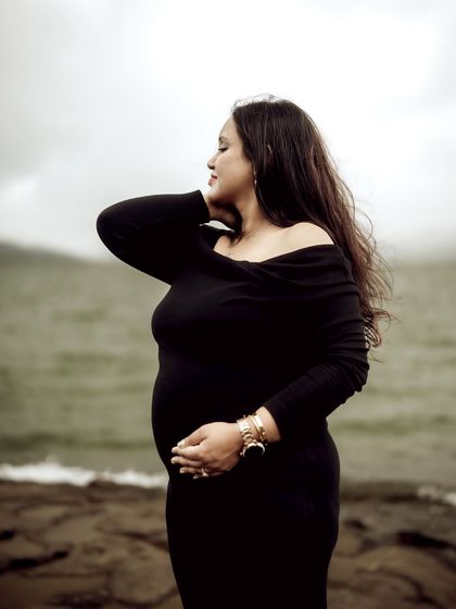 A close-up portrait of the mom-to-be by the water, with the wind in her hair. Her eyes are closed, capturing a moment of peaceful connection with nature.