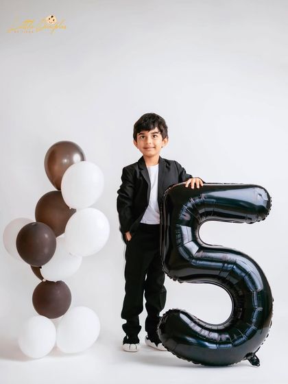 A proud stance next to a giant number '5' balloon. Milestone sessions are a fantastic way to mark these important birthdays and see how much they've grown.