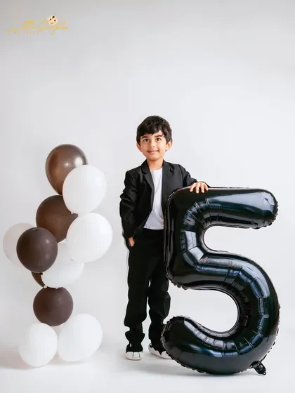Posing with his age. Using balloon numbers is a fun way to mark the occasion in a milestone photoshoot.