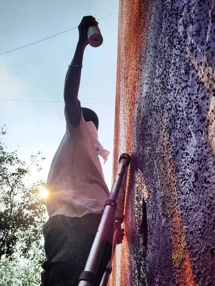 Me on the ladder, adding details to the Ed Sheeran mural as the sun sets. Projects of this scale require precision, teamwork, and a lot of time spent high above the street.