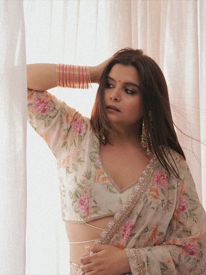 Another angle of the floral saree look, capturing a candid moment. The makeup is designed to look fresh and natural in soft, diffused light, perfect for daytime events or photoshoots.