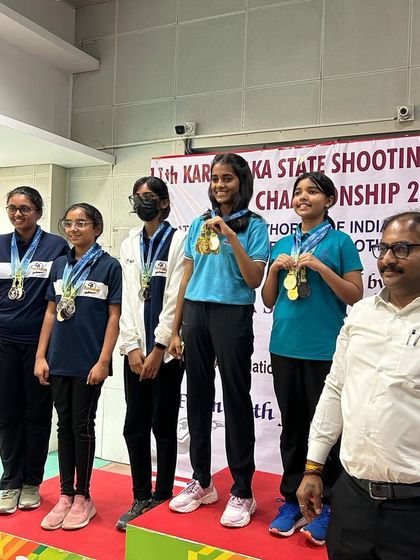 The Air Pistol women's team on the podium, displaying their medals won through teamwork and dedication.