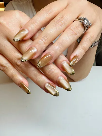 A closer look at the liquid-gold effect of this cat-eye manicure, accented with a touch of black at the tips for extra definition.