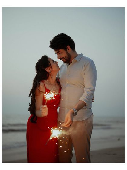 The warm glow of sparklers illuminates the couple's faces as they share a look of love during their romantic beach pre-wedding session.