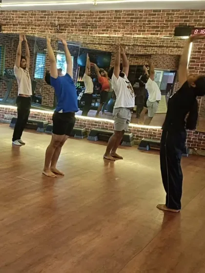 Group energy is powerful. Here, the class moves together through an upward salute, a fundamental yoga asana for improving posture and breathwork.