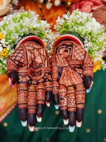 A beautiful shot of the bride's hands after the henna has stained. The dark, rich color highlights the intricate details of the wedding figures and patterns.