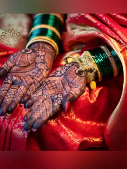A beautiful photo of the bride's hands against her red saree. The contrast between the dark mehndi and the bright fabric is striking.