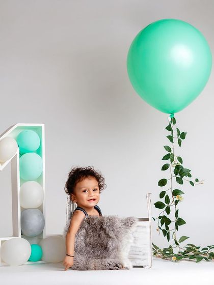 Simplicity can be so beautiful. This minimalist first birthday setup with a single balloon and clean background keeps the focus entirely on the child.