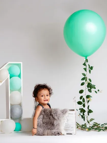 Simplicity can be so beautiful. This minimalist first birthday setup with a single balloon and clean background keeps the focus entirely on the child.