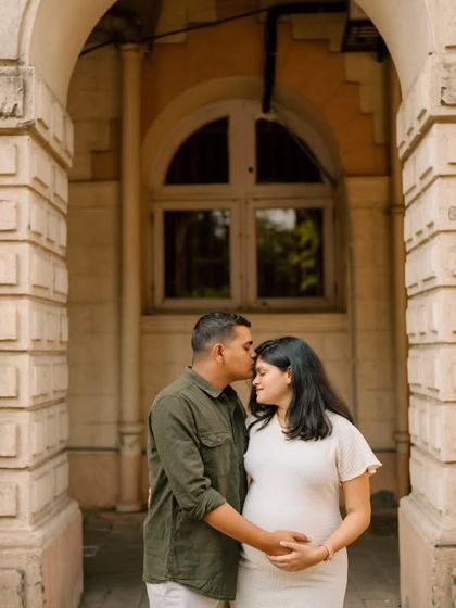 A tender moment shared between the couple against the backdrop of classic stone architecture, symbolizing the strong foundation of their growing family.
