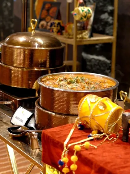 A beautifully decorated main course station with copper serving dishes, part of a Punjabi-themed event setup.