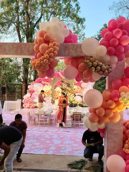 A beautiful outdoor setup for a peach and pink teddy bear themed party. This wide shot shows the full arrangement, including the entrance arch and the main stage, creating a cohesive and inviting atmosphere for guests.