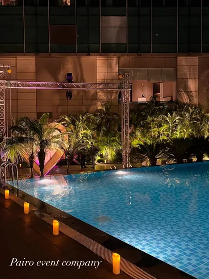 A wide view of the poolside proposal area before the main event, showing the lighting truss and the heart structure, giving a sense of the scale of the setup.