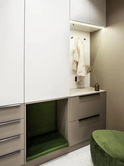 This entryway storage unit is designed for maximum utility. It features cabinets for shoes, drawers for small items, and a comfortable seating nook in a vibrant green, making it both practical and welcoming.