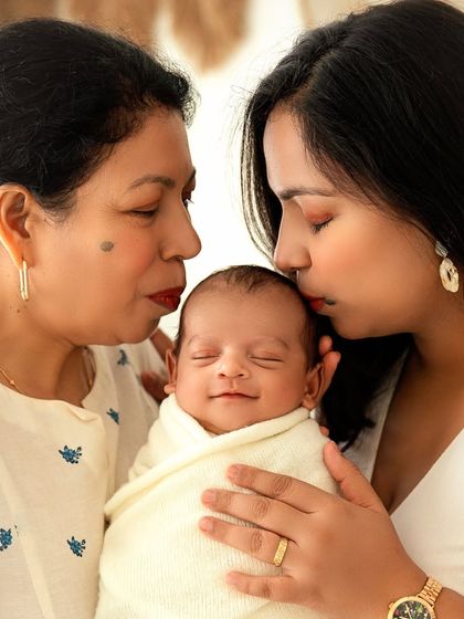 A grandmother and mother share a kiss with the newest member of the family. A truly precious moment filled with cross-generational love.