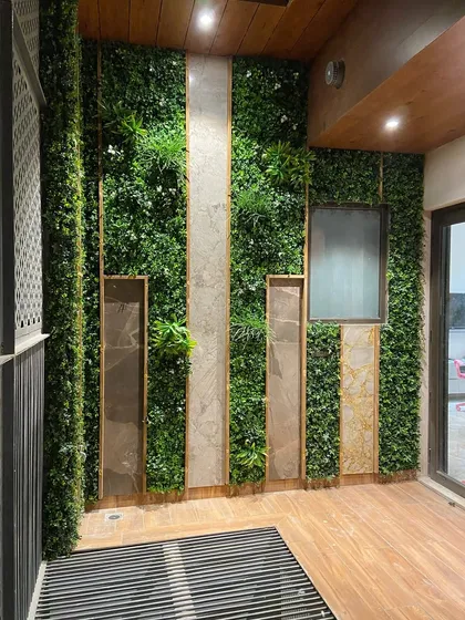 A balcony wall in Faridabad is given a major upgrade with this design. Panels of artificial vertical gardens are framed by stone-look tiles and wood, creating a sophisticated and low-maintenance feature wall.