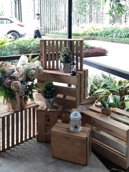 Rustic wooden crates and lanterns are used as decorative elements to add a charming and warm touch to the entrance of the dinner party.
