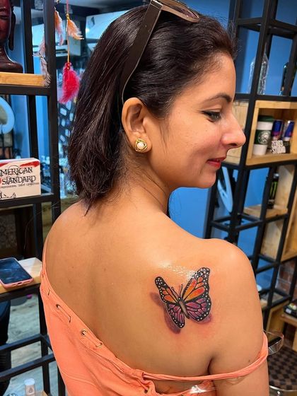 A beautiful 3D-style butterfly tattoo on the shoulder, part of a friendship tattoo session.