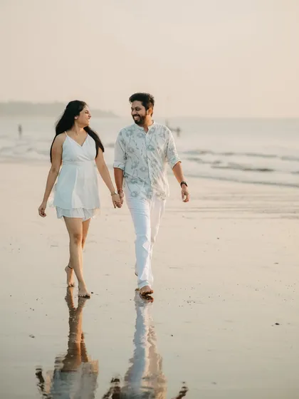 Walking hand-in-hand into our forever. A classic, romantic pre-wedding photograph on the beach as the sun sets, capturing the simple joy of being with the one you love.