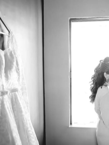 A black and white getting-ready shot of the bride by the window. The contrast between the bride and her dress creates a beautiful, classic composition.