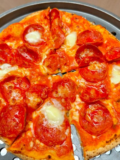 A close-up of our classic pepperoni pizza, fresh out of the oven. The glistening pepperoni and melted mozzarella on a perfectly cooked crust show the delicious quality we serve at every event.