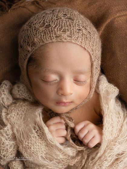 This two-week-new honey pie is wrapped in earthy brown tones, looking cozy and content. The delicate knit bonnet and wrap add beautiful texture to the portrait.