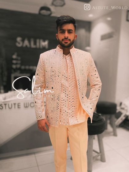 A client wearing a peach-colored Indo-Western jacket with all-over mirror work. This is a lighter, festive option perfect for daytime events or a sangeet ceremony.