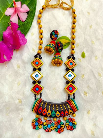 A beautiful and unique necklace with a multi-colored floral hanging pendant. The chain features geometric beads, creating a wonderful fusion of styles.