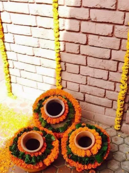 A simple and traditional decor element using earthen matkas. I decorated the mouth of each pot with marigold and green leaves, and placed them together as a showpiece.