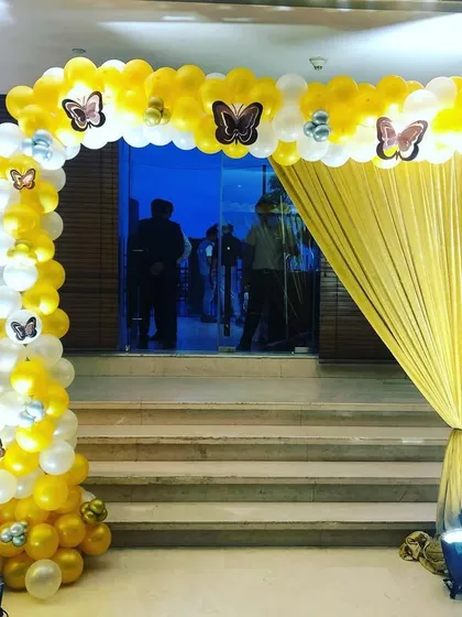 A cheerful yellow and white balloon arch for a birthday party entrance. The butterfly details add a touch of whimsy to the celebration.