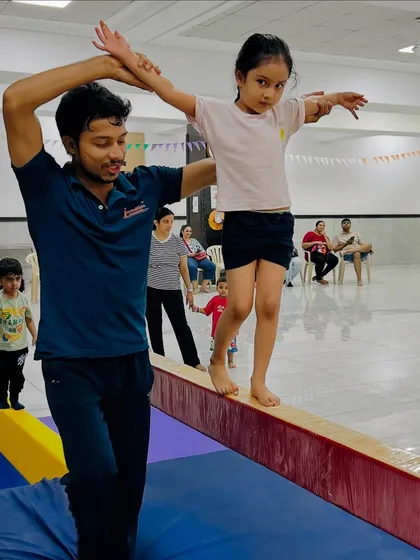 Every step on the beam is a lesson in focus and trust. Here, I am personally guiding one of our young gymnasts, ensuring she feels safe and supported as she builds her balance and coordination. This hands-on approach is at the heart of our coaching.