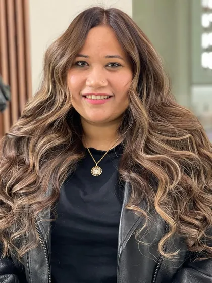 A finished look of a beautiful balayage with soft curls, showing the incredible dimension and texture that can be achieved.